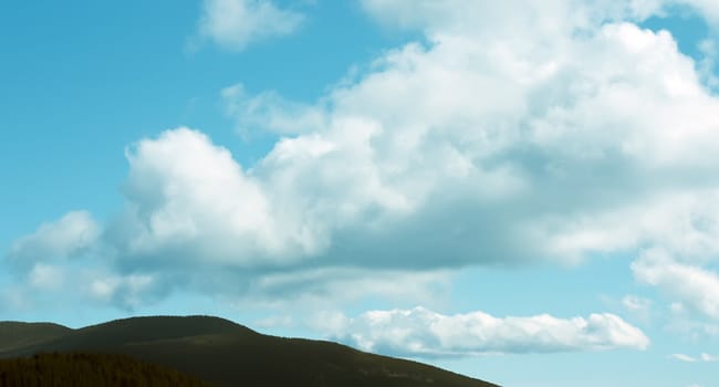 Big clouds in green mountains in sunny day