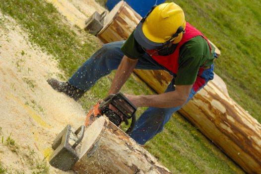 A woodcutter trimming a log with a chainsaw, the sawdust flying.