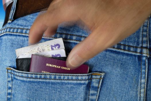 A wallet with �20 notes and a passport poke out of the rear pocket of a traveller's jeans. Motion blur on a pickpocket's hand, about to take them.