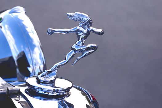 A bonnet (hood) ornament on the front of a veteran car.