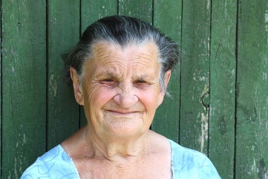 Grandma sat down on a bench near the courtyard and looks forward to the children and grandchildren to visit