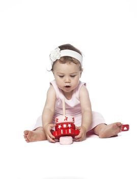 Baby in pink clothes playing with a red toy isolated on white