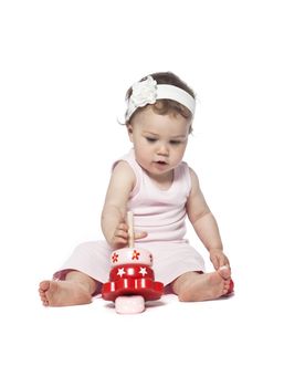Baby in pink clothes playing with a red toy isolated on white