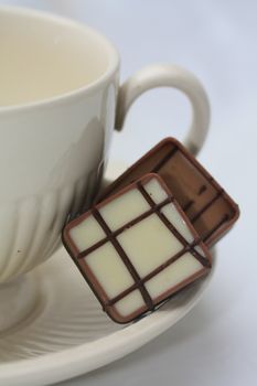 Two luxury chocolates on a tea cup saucer