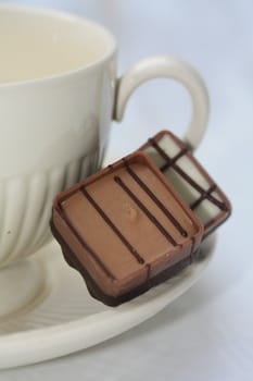 Two belgium chocolate pralines on a tea cup saucer