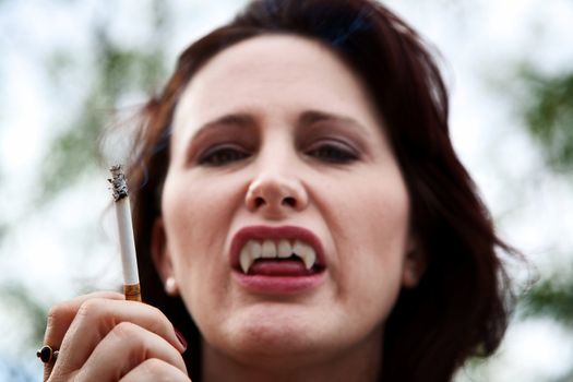 Female vampire smoking a cigarette and baring her teeth