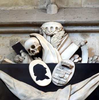 Memento mori (Remember thou shalt die) - Ancient medieval sculpture with skull and reaper's sickle in Koelner Dom cathedral, Koeln, Germany