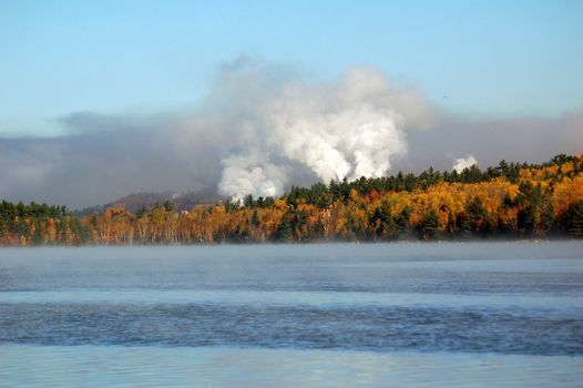 Picture of a colorful autumn landscape with morning fog and smokes