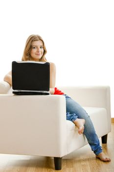 Beautiful young woman sitting on a sofa and working on a laptop