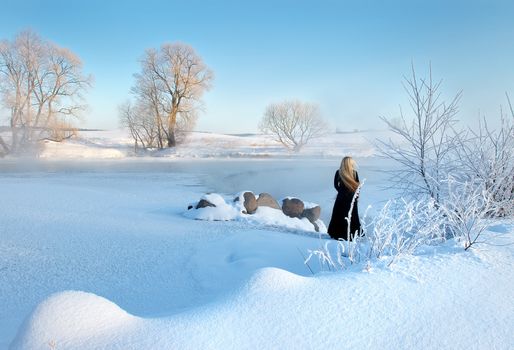 Frosty winter morning in Belarus, the girl about the frozen reservoir.