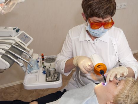 The stomatologist carries out photopolymerization of the sealed up tooth