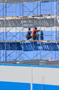 Two workers on industrial object surrounded with designs