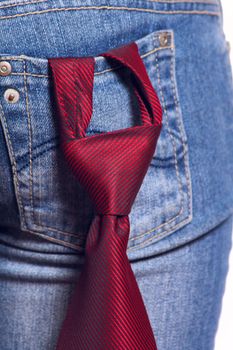 Red striped tie stuck in knot and being in a pocket female jeans removed close up