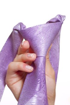 Female hand holding a violet tie with the fastened knot removed close up