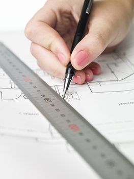 Female architect working on a bluprint, close up on hand and bluprint.