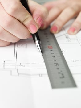 Female architect working on a bluprint, close up on hand and bluprint.