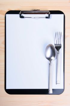 Spoon and fork on Blank Clipboard, as one of design elements to kitchen subjects.