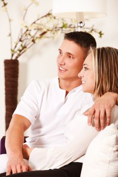 Smiling young couple sitting on sofa relaxing