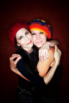 Two pretty female friends hugging and wearing knit hats