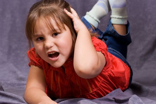 A four year old girl holding her head in pain