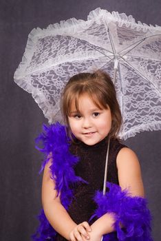 A four year old girl holding a lace umbrella getting her portrait done and wearing a feather boa