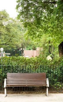 It is a brown bench with nobody in the park.
