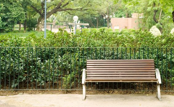 It is a brown bench with nobody in the park.