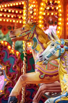 A detailed image of two ornate hand carved horse figure on a fairground carousel ride.