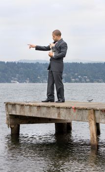 Ethnic Business Man Pointing and Yorkshire Terrier Dog standing on a pier next to the lake.