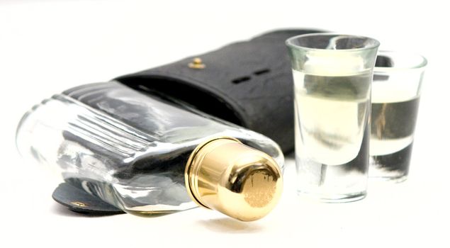 Shot Glasses with Whiskey Alcohol flask and case on a white background. The flask has a brass cap. 