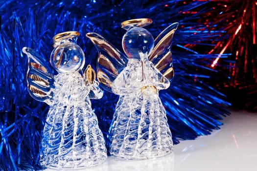 Two decorative glass angel and Christmas tree tinsel on white with reflections