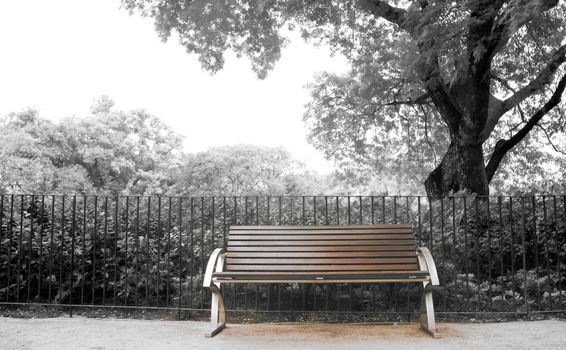 It is a brown bench with nobody in the park.