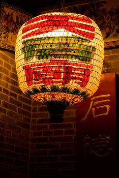 It is a yellow Chinese lantern in front of old house.