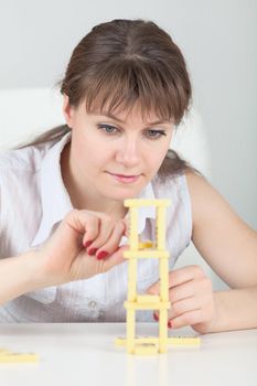 The young girl builds a tower of dominoes bones on a table