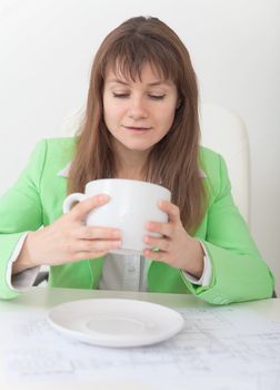 The woman looks in a huge cup for coffee