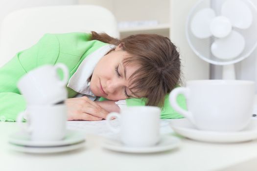 The woman has got tired and sleeps on a table among coffee cups