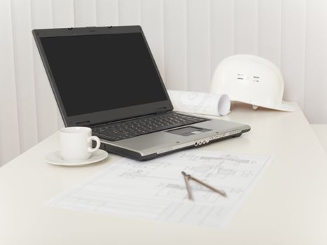 The laptop, drawings, helmet and compasses on a white table