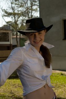 Portrait of a woman in a white shirt and cowboy hat on a ranch.