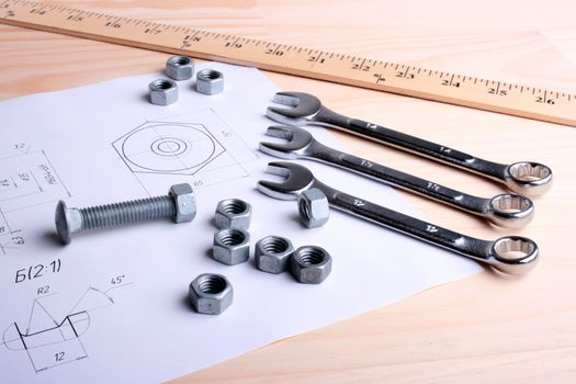 Set of wrenches, nuts and a bolt against the drawing of a nut and rolls of schemes. Working conditions.