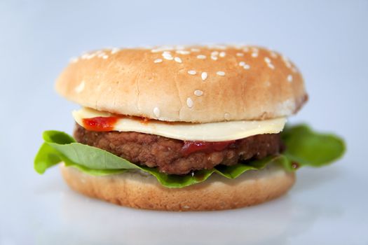 cheeseburger with salad and tomato over a gray background