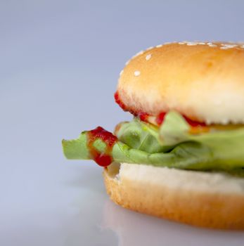 cheeseburger with salad and tomato over a gray background