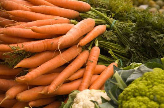 Fresh carrots, cauliflowers and broccoli on a market stall.