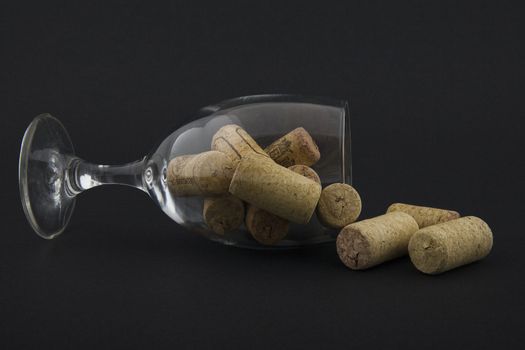 wineglass filled with corks on dark background