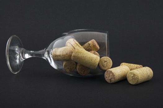 wineglass filled with corks on dark background