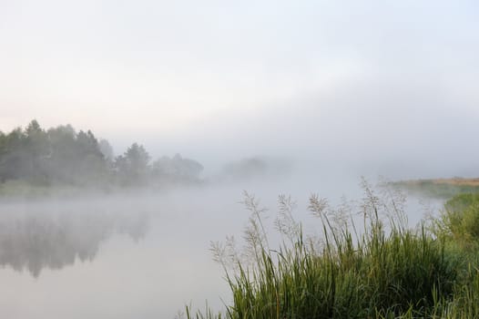 The sunrise, over the river rises a morning fog.