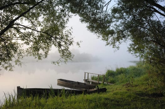 Sunrise, boats at coast in a morning fog. 