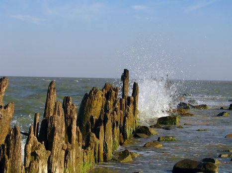 Old wooden breakwater and sail on horizon. (2)