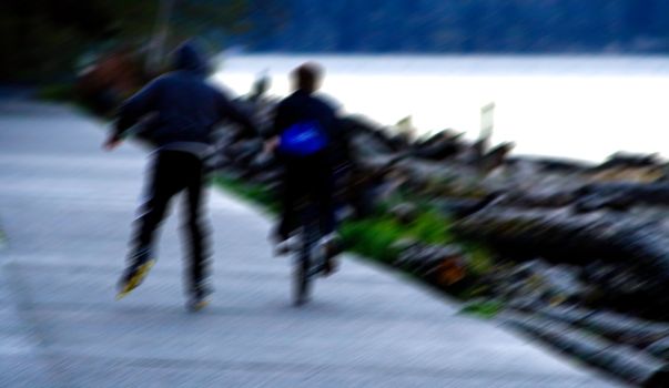 Biker and Roller Blader Blur is a capture along the boardwalk at Point Defiance Washington next to the waters of Puget Sound.
