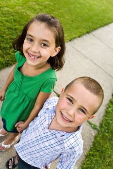 Two little kids holding hands as they walk down the sidewalk.  Plenty of copy space for your text.