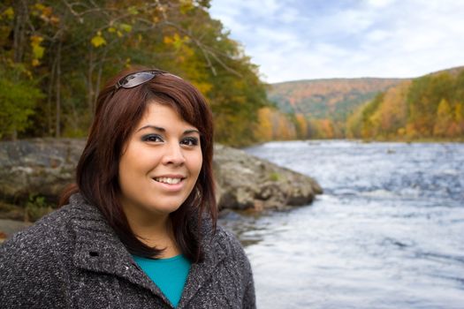 A young plus sized model posing by a river in New England during Autumn.